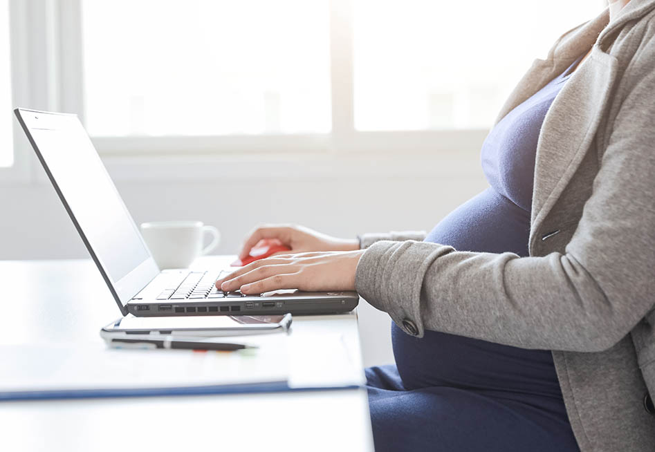pregnant woman wokring on laptop possibly facing pregnancy discrimination at work