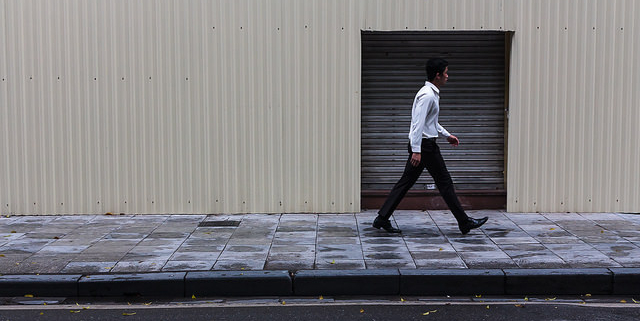 man walking past wall reflecting employee who has been victim of constructive dismissal walking away from his workplace