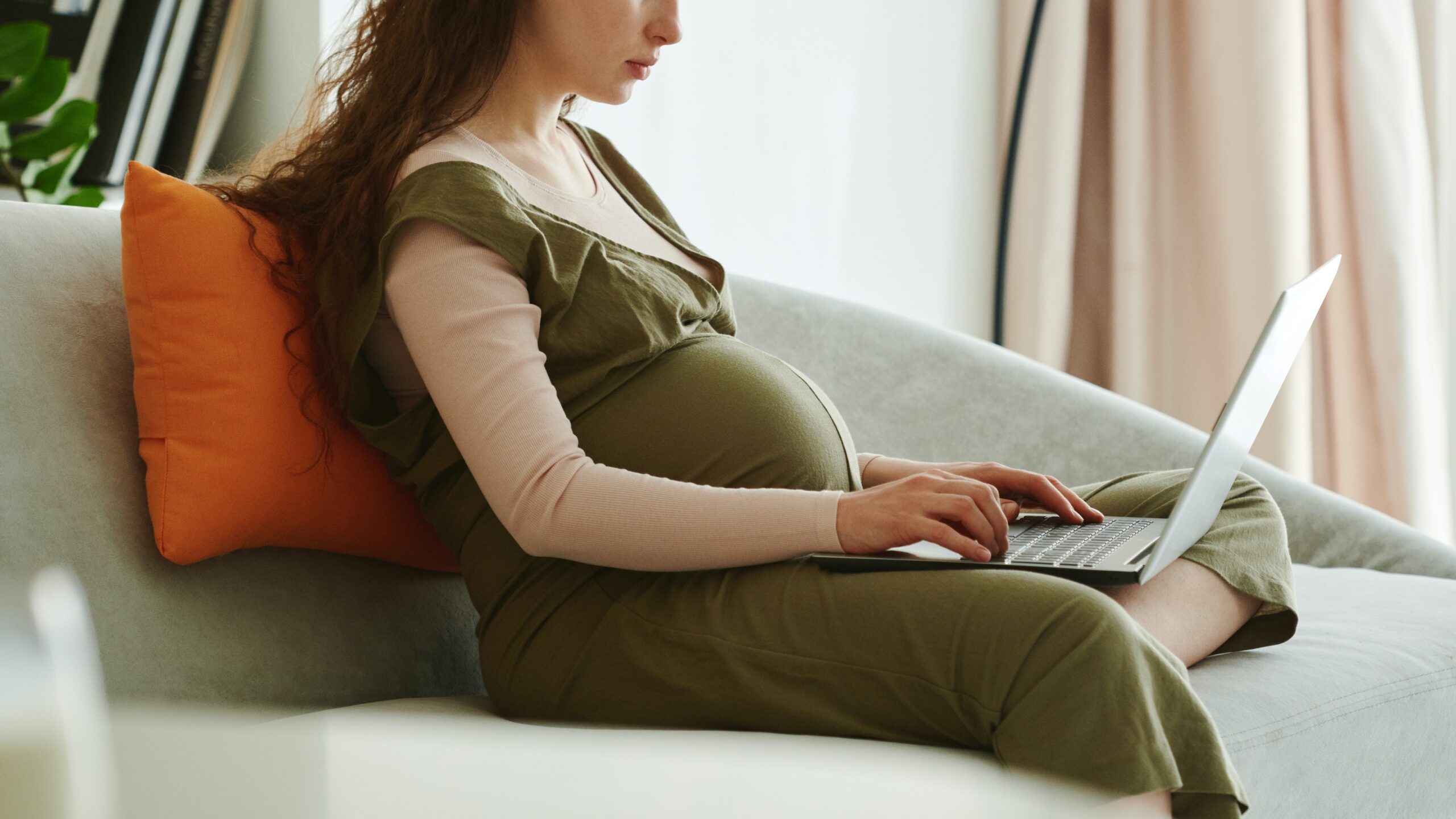 Pregnant woman working on a laptop to reflect someone being discriminated against for a protected attribute