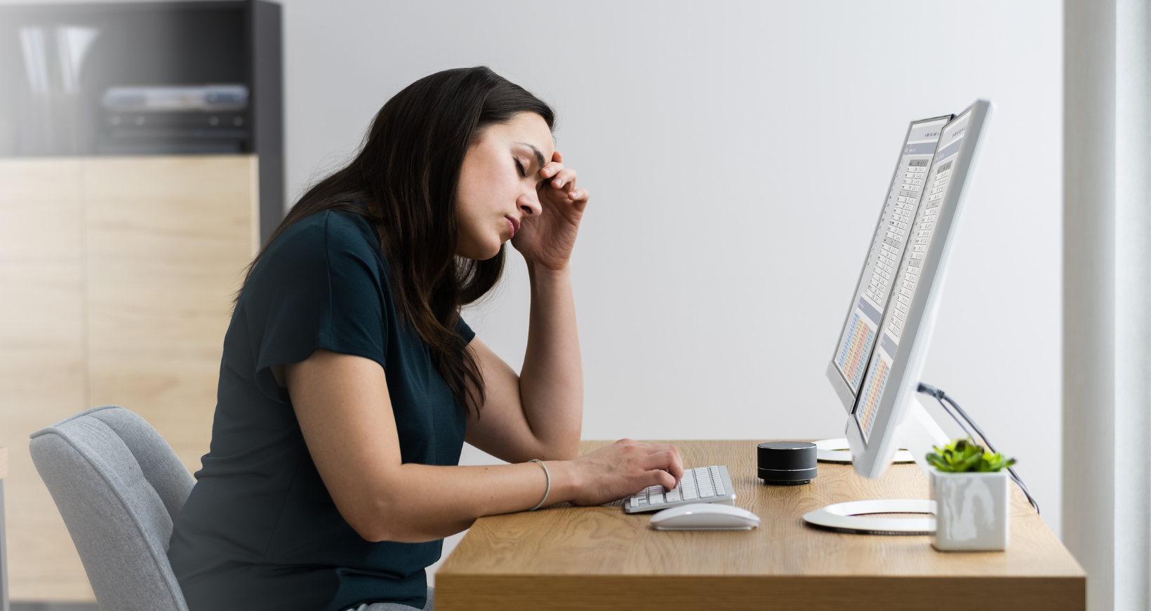 Image of a woman resting head in hand sitting at computer to represent an employee facing discrimination