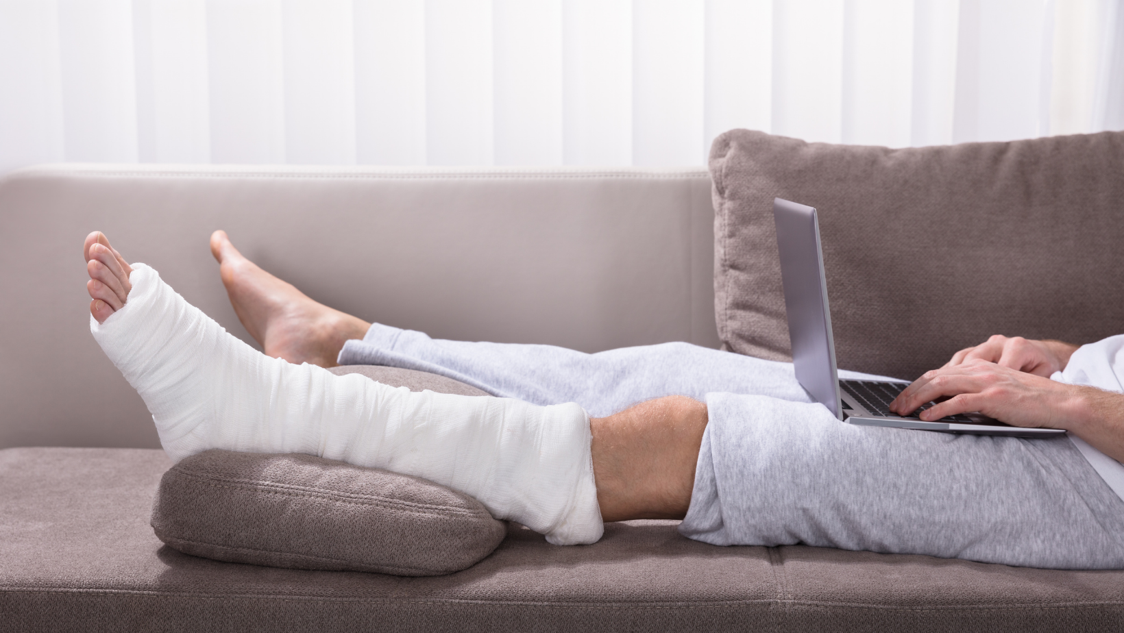 Employee working on laptop on couch due to illness or injury