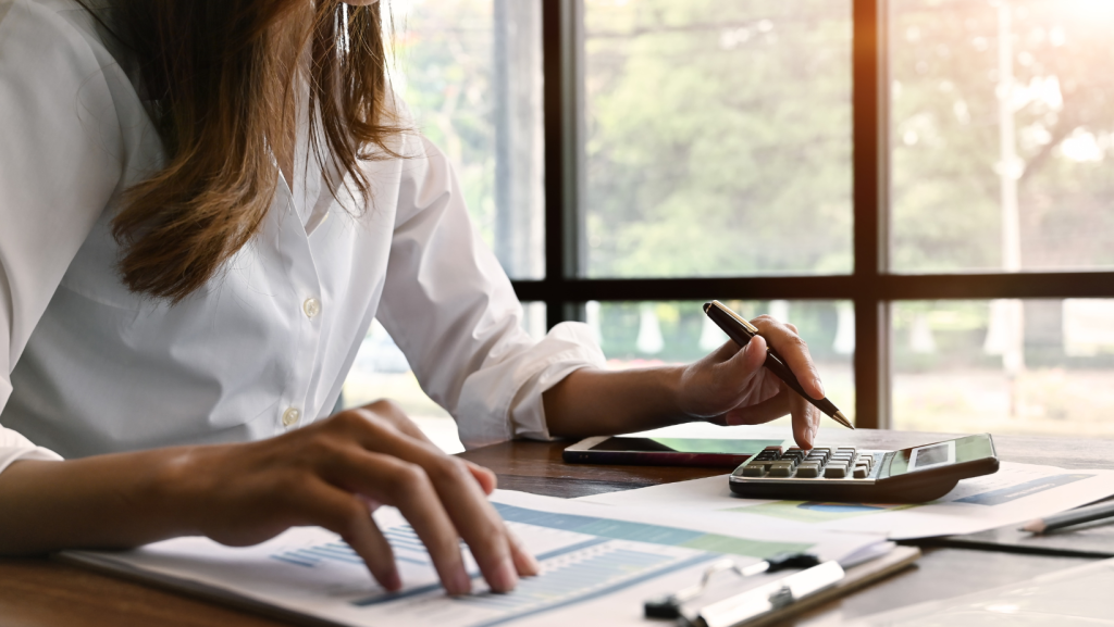 Woman using calculator reflecting calculating minimum wage increases for employees