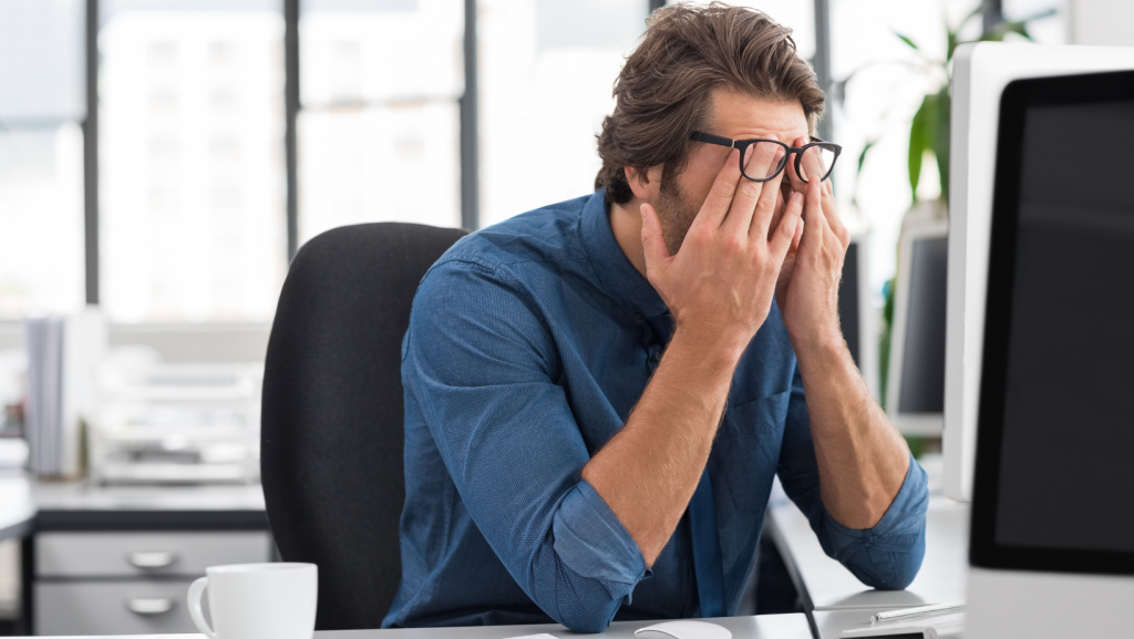 Employee sits with head in his hands at desk after demotion