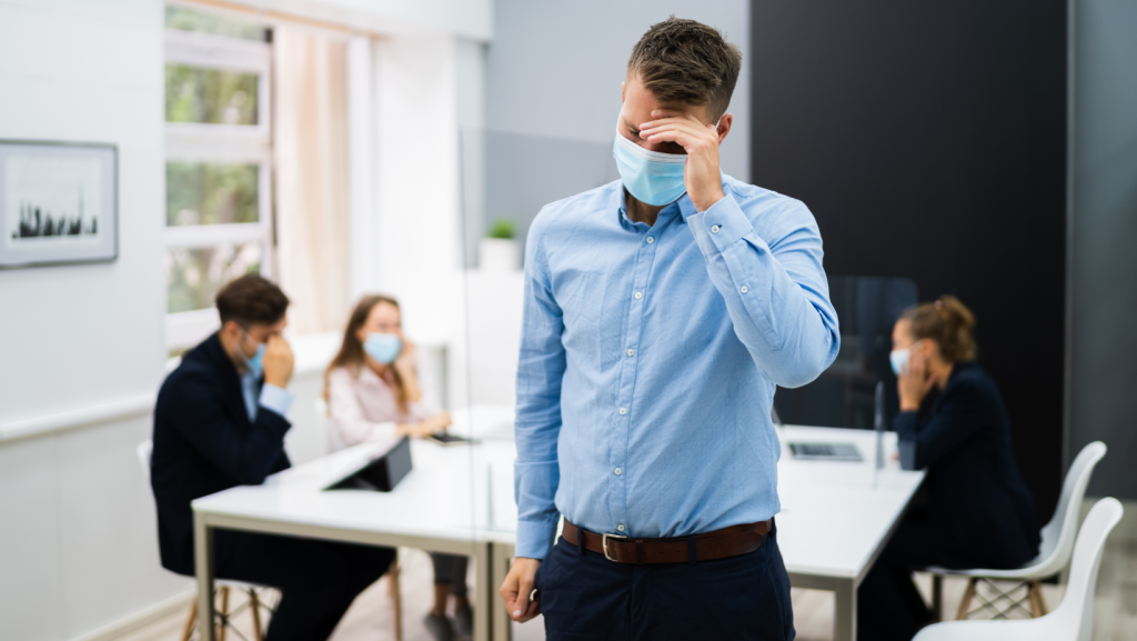 Male employee being bullied by three co-workers in the background to represent an employee considering making a stop bullying application