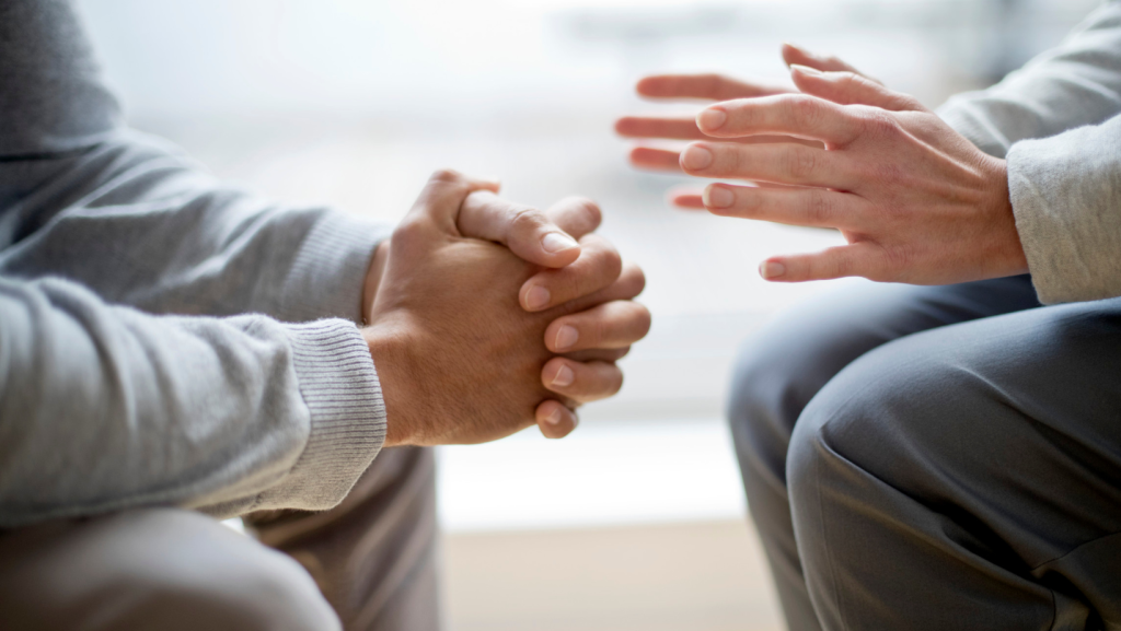 Close up of two peoples hands during counselling session for family and domestic violence